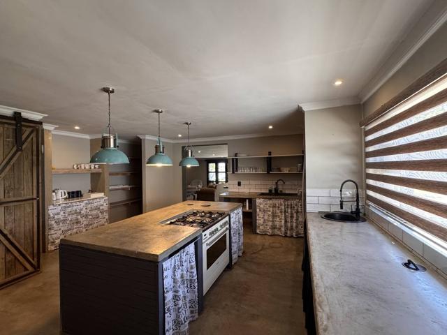 Gas hob island under teal pendant lights in the Stoneridge Cottage kitchen