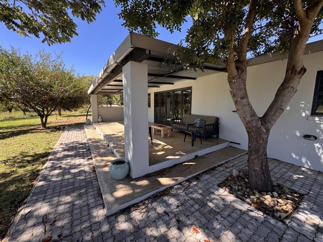 Covered stoep and paved garden under shade trees at Stoneridge Cottage