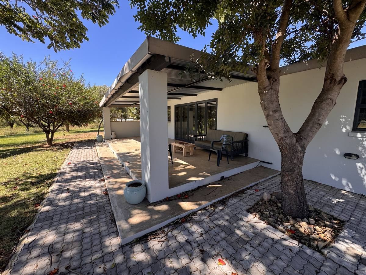 Covered stoep and paved garden under shade trees at Stoneridge Cottage